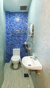 Baño de azulejos azules con aseo y lavamanos en Island Guesthouse - Previously known as Islander Lodge, en George Town