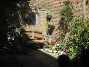 eine Holzbank neben einer Backsteinmauer in der Unterkunft Cosy character cottage conservation area in St Albans