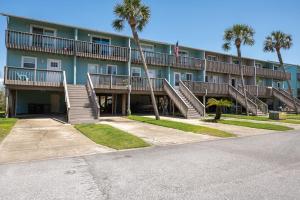 a large apartment building with stairs and palm trees at Sandy Dreams - 2B Townhome in Pensacola Beach