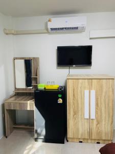 a room with a refrigerator and a tv on a wall at ตาแอกะยายแดงโฮมสเตย์ in Ban Hong Khu