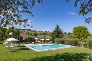 a swimming pool in a yard with chairs and umbrellas at Casal La Ponderosa in SantʼElpidio a Mare