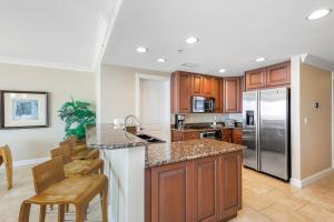 Una cocina con gabinetes de madera y electrodomésticos de acero inoxidable. en Beach Club Gulf Front 3B Condo - 502, en Pensacola Beach