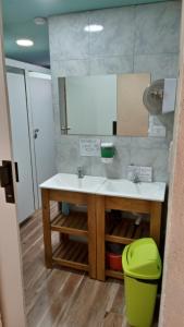 ein Badezimmer mit einem Waschbecken und einem grünen Mülleimer in der Unterkunft Los Milenarios in El Chalten