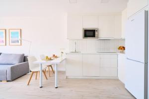 a white kitchen with a table and a couch at OleHolidays 821 Romana Playa frente al mar in Marbella