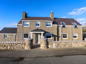 a large brick house with a stone wall at Ty'n Ffridd in Pwllheli