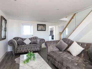 a living room with two couches and a staircase at Ty'n Ffridd in Pwllheli