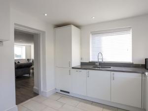 a kitchen with white cabinets and a sink at Ty'n Ffridd in Pwllheli +32 photos