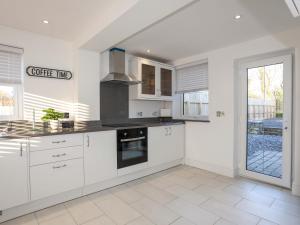 a kitchen with white cabinets and a large window at Ty'n Ffridd in Pwllheli