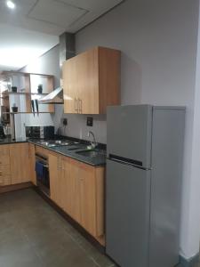 a kitchen with a white refrigerator and wooden cabinets at Isibaya House in Johannesburg
