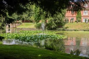 a garden with a fountain in the middle of a pond at Albrighton Hall Hotel and Spa, a member of Radisson Individuals in Shrewsbury