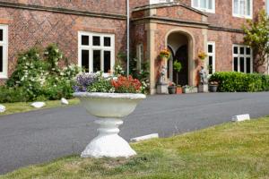 a white vase with flowers in front of a building at Albrighton Hall Hotel and Spa, a member of Radisson Individuals in Shrewsbury +147 photos