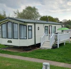 a small white house with a porch and an umbrella at Pebbles holidays in Sandown