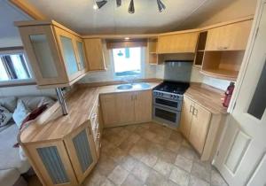 a small kitchen with wooden cabinets and a sink at Pebbles holidays in Sandown