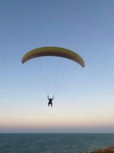 a person is flying with a parachute over the ocean at Portal do Sol in Canoa Quebrada