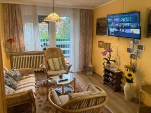 a living room with a couch and chairs and a tv at Ferienwohnung Sonnenblume in Leer