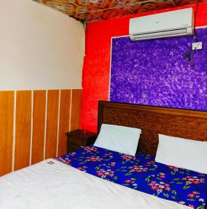 a bedroom with a bed and a purple wall at City Palace Hotel Lahore in Lahore