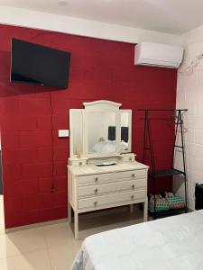 a bedroom with a white dresser and a red wall at Tres Soles 2 in Salsipuedes
