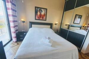 1 dormitorio con 1 cama blanca grande y espejo en Kyparissia Bliss, en Kyparissia