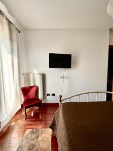 sypialnia z telewizorem na ścianie i czerwonym krzesłem w obiekcie Dolce Ricordo, locazione turistica w mieście Marano Vicentino +23 zdjęcia
