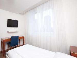 1 dormitorio con 2 camas, escritorio y ventana en Swiss Star Marc Aurel - Self Check-In en Zúrich