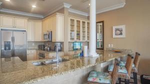 a kitchen with a counter with a sink and a refrigerator at Beach Club Gulf Front 3B Condo - 1703 in Pensacola Beach