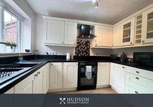 a kitchen with white cabinets and a stove top oven at 3 Bedroom House with Garden in Admaston