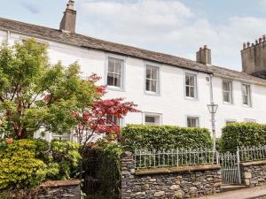 a white house with a fence and bushes at Middletown in Keswick