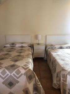 a bedroom with two beds and a lamp on a night stand at VUT Rural 2 in Arzúa
