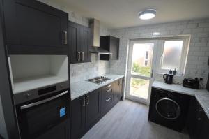 eine Küche mit schwarzen Schränken, einem Waschbecken und einem Fenster in der Unterkunft Regent House in Seven Kings