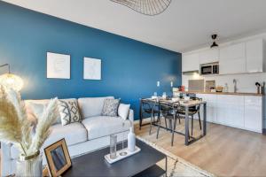 a living room with a white couch and a blue wall at Appartement Megara in Montévrain +8 photos