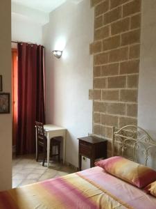 a bedroom with a bed and a table and a brick wall at U' Iazzu in Avola
