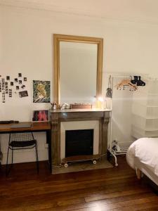 a bedroom with a fireplace and a bed and a mirror at Full house Canal Saint-Martin in Paris