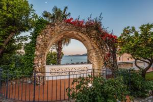 an archway with a stone fence and red flowers at Villa Irlanda Grand Hotel in Gaeta