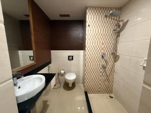 グワーハーティーにあるMW Hotelのトイレ、洗面台、シャワー付きのバスルーム