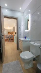 a white bathroom with a toilet and a sink at Cozy Bungalow in Tríkala