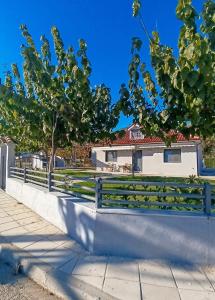 a fence in front of a house with a tree at Cozy Bungalow in Tríkala
