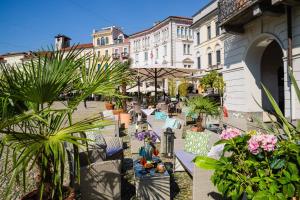 a street with tables and chairs and plants and buildings at Hotel America in Locarno
