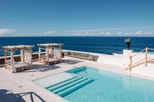 a swimming pool with chairs and the ocean in the background at Boutique Eco Hotel Costa Mágica in La Laguna