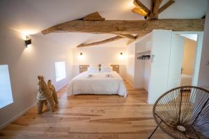 a bedroom with a white bed and a wooden floor at L'Odissée in Mazeray