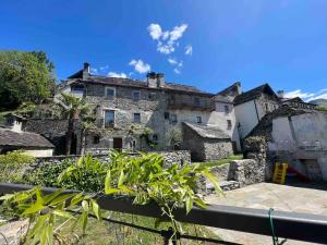an old stone house with a fence in front of it at Antica Casa Rivoira Ciliegio in Masera