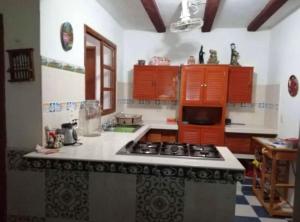 La cuisine est équipée d'armoires orange et d'un four avec plaques de cuisson. dans l'établissement Casa de campo Huerta De Calín, à Valladolid