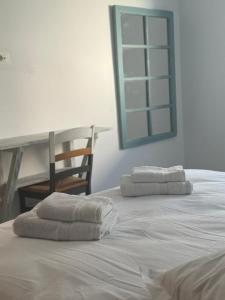 een wit bed met twee handdoeken erop bij Les portes délavées in Sfax