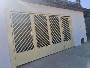 a wooden gate on a white garage door at Espaço Tranquilo-preço até 4 hóspedes in Pôrto Feliz