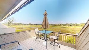 a balcony with a table and chairs and an umbrella at Getaway to the Beach 2 Bdrm Villa with Amenities in Pawleys Island