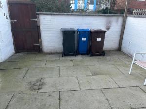 due bidoni della spazzatura seduti accanto a un muro di mattoni di Skyline Self Service a Leigh