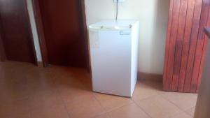 a white refrigerator in a room with a floor at 33 On Swallows Guest House in Soshanguve