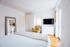 a white bedroom with a bed and a chair at Casa e Arte in Sorrento