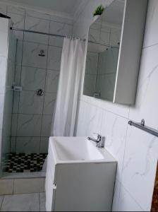 Un baño con lavabo y ducha con espejo. en Lindokuhle Holiday Accommodation, en Durban