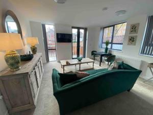 ein Wohnzimmer mit einer grünen Couch und einem Tisch in der Unterkunft Ranmoor Serviced Apartments at Wilkinson Lane- The Burlington Suite in Sheffield