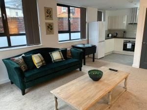 ein Wohnzimmer mit einer grünen Couch und einem Tisch in der Unterkunft Ranmoor Serviced Apartments at Wilkinson Lane- The Burlington Suite in Sheffield